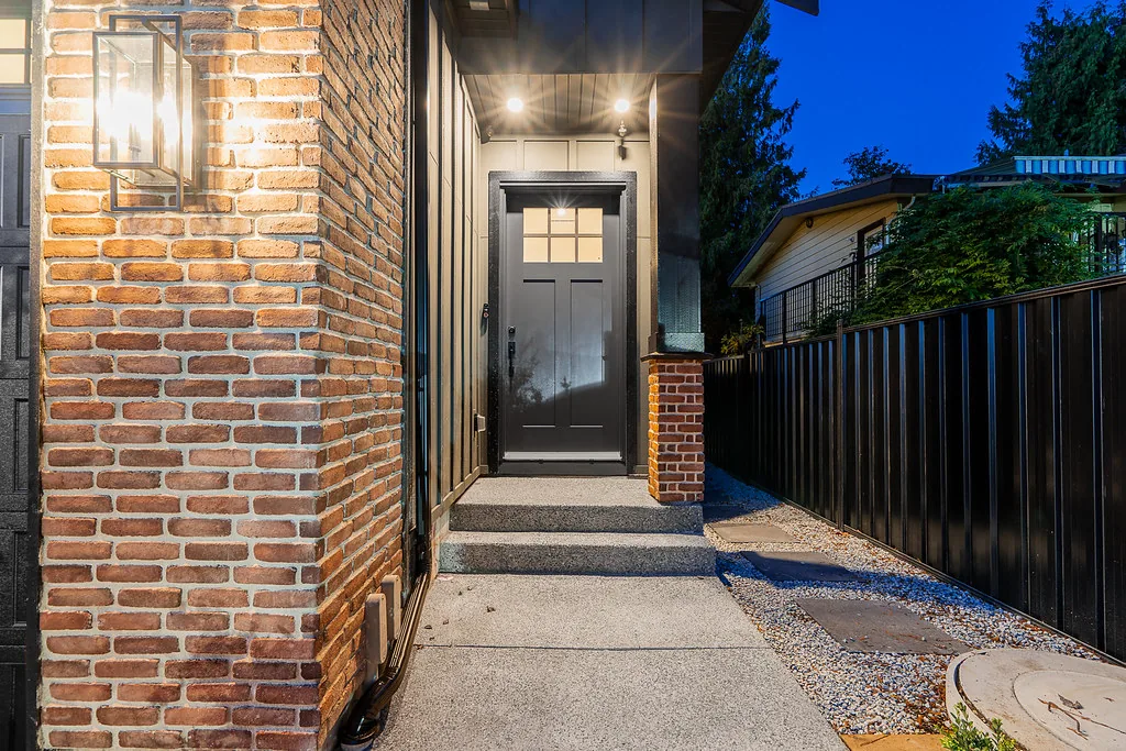 Brick entry with black front door and sconce
